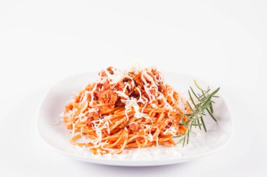 Biberiye dalıyla süslenmiş ve üzerine peynir serpiştirilmiş bir tabak spagetti bolonez.