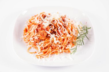 Biberiye dalıyla süslenmiş ve üzerine peynir serpiştirilmiş bir tabak spagetti bolonez.