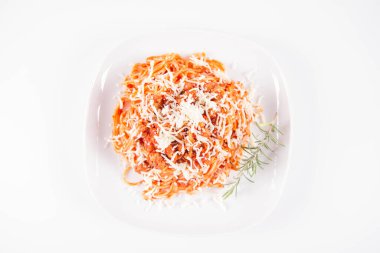 Biberiye dalıyla süslenmiş ve üzerine peynir serpiştirilmiş bir tabak spagetti bolonez.