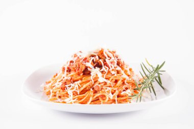 Biberiye dalıyla süslenmiş ve üzerine peynir serpiştirilmiş bir tabak spagetti bolonez.