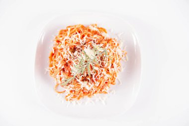 Biberiye dalıyla süslenmiş ve üzerine peynir serpiştirilmiş bir tabak spagetti bolonez.