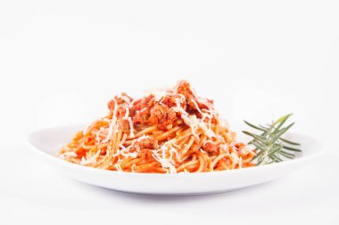 Biberiye dalıyla süslenmiş ve üzerine peynir serpiştirilmiş bir tabak spagetti bolonez.