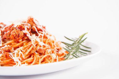 Biberiye dalıyla süslenmiş ve üzerine peynir serpiştirilmiş bir tabak spagetti bolonez.