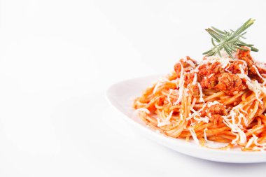 Biberiye dalıyla süslenmiş ve üzerine peynir serpiştirilmiş bir tabak spagetti bolonez.