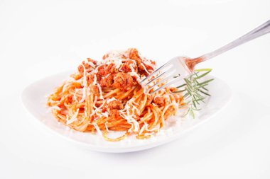 Biberiye dalıyla süslenmiş ve çatalla yenmiş peynirli spagetti bolonez.