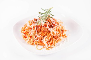 Biberiye dalıyla süslenmiş ve üzerine peynir serpiştirilmiş bir tabak spagetti bolonez.