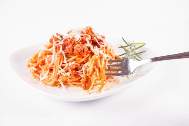 Biberiye dalıyla süslenmiş ve çatalla yenmiş peynirli spagetti bolonez.