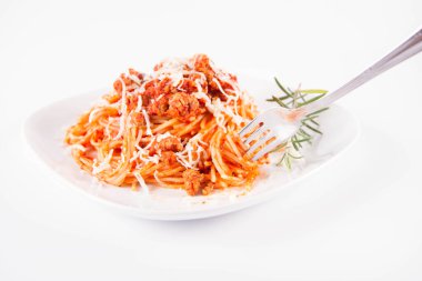 Biberiye dalıyla süslenmiş ve çatalla yenmiş peynirli spagetti bolonez.