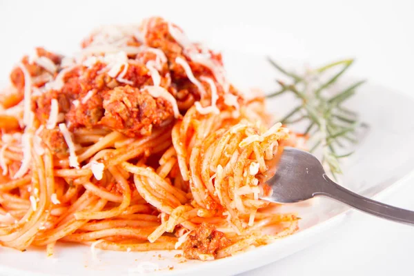 Biberiye dalıyla süslenmiş ve çatalla yenmiş peynirli spagetti bolonez.