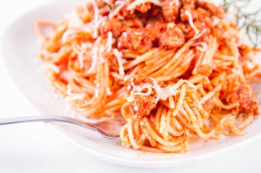 Çatalla yenmiş peynirle kaplı bir tabakta spagetti bolonez.