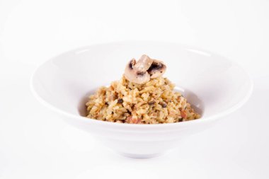 Mantarlı risotto ve beyaz arka planda mantarla süslenmiş domuz pastırması.