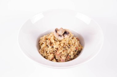 Mantarlı risotto ve beyaz arka planda mantarla süslenmiş domuz pastırması.
