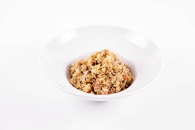 Düğme mantarlı risotto ve beyaz arka planda bir tabak domuz pastırması.