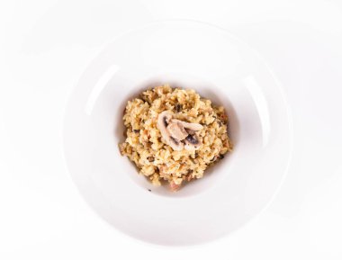 Mantarlı risotto ve beyaz arka planda mantarla süslenmiş domuz pastırması.
