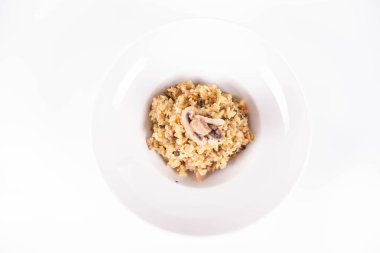 Mantarlı risotto ve beyaz arka planda mantarla süslenmiş domuz pastırması.
