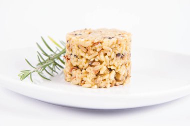 Düğme mantarlı risotto ve beyaz arka planda bir tabakta biberiye dalı ile süslenmiş pastırma.