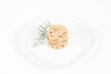 Düğme mantarlı risotto ve beyaz arka planda bir tabakta biberiye dalı ile süslenmiş pastırma.