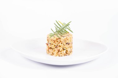 Düğme mantarlı risotto ve beyaz arka planda bir tabakta biberiye dalı ile süslenmiş pastırma.