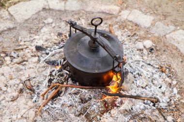 Geleneksel bir tencere et ve sebze pişirme şenlik ateşinin üzerinde dökme demir bir kazanda