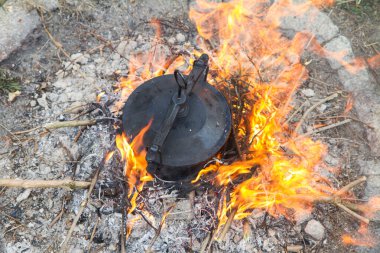 Geleneksel bir tencere et ve sebze pişirme şenlik ateşinin üzerinde dökme demir bir kazanda