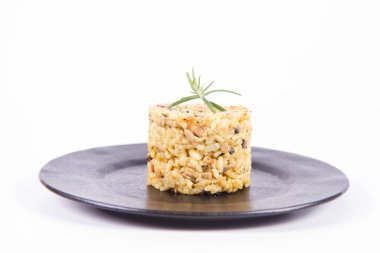 Düğme mantarlı risotto ve beyaz arka planda siyah bir tabakta biberiye dalı ile süslenmiş domuz pastırması.