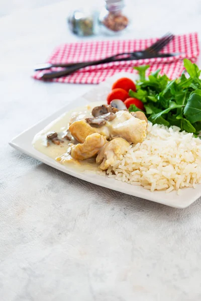 Pieces of chicken fillet cooked in a cream sauce with mushrooms and lemon juice, served with rice.