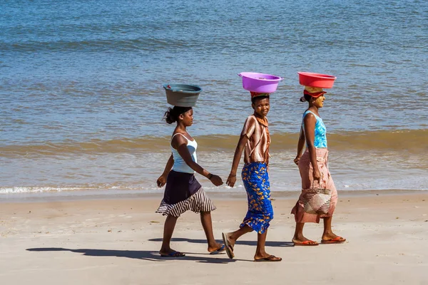 Mujeres malgaches llevando cuencas sobre sus cabezas caminando en la playa de Amborovy cerca de Mahajanga (Majunga), Madagascar el 27 de agosto de 2016 . —  Fotos de Stock