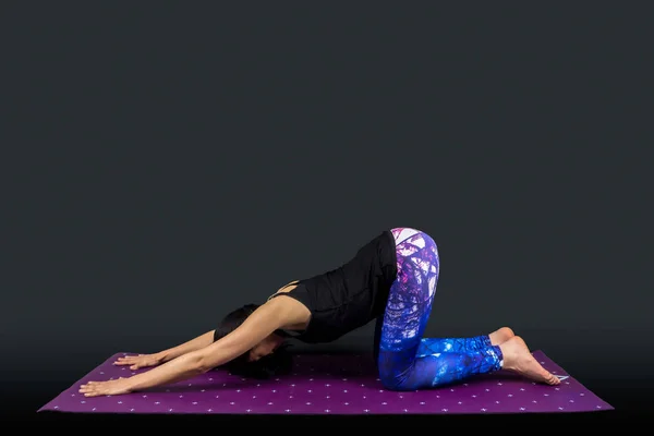 A woman yoga teacher in uttana shishosana posture — ストック写真