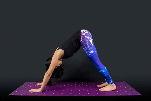 Een vrouw yoga leraar in adho mukha svanasana houding — Stockfoto