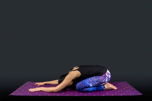 Een vrouw yoga leraar in balasana garbhasana houding — Stockfoto