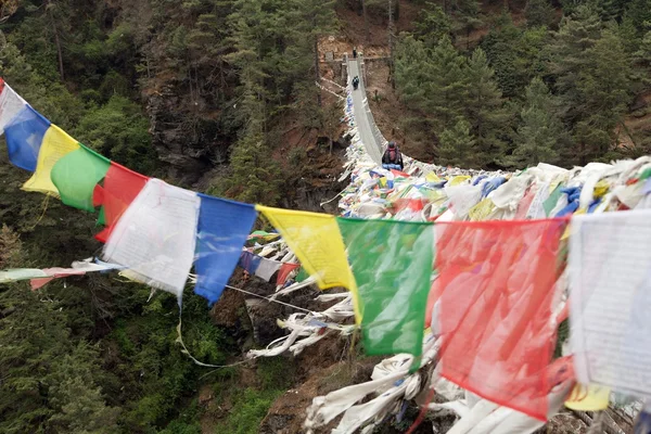 Rope hunging suspension bridge with row of prayer flags — Stock Photo, Image