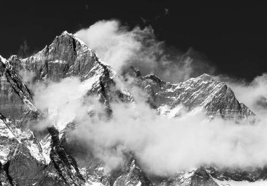 Bulutlar üstünde belgili tanımlık tepe ile Lhotse Dağı
