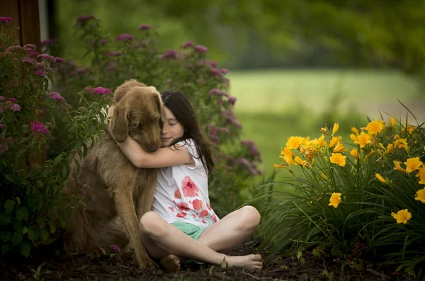 Beautiful girl hugging dog in garden — Stock Photo, Image