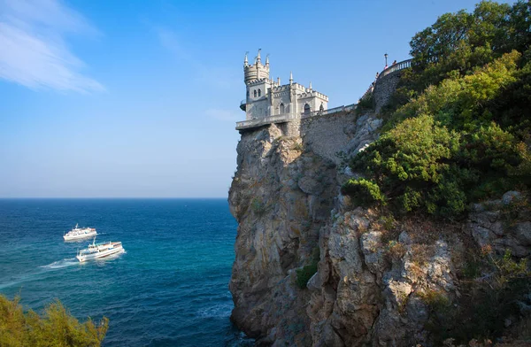 Una vista del romántico palacio Swallow Nest, erigido en un acantilado, en el fondo del mar y las rocas, cruceros embarcaciones de recreo. Crimea Imágenes de stock libres de derechos