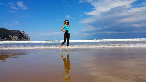 Chica con cámara caminando en el agua en la playa — Foto de Stock