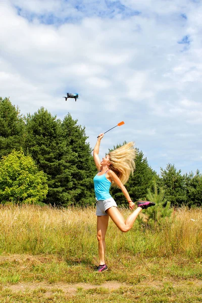 The blonde girl  with a fly swatter drives away drone — Stock Photo, Image