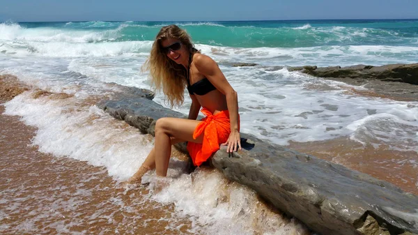 Sarışın siyah bikini ve güneş gözlüğü ve sahilde turuncu pareo — Stok fotoğraf