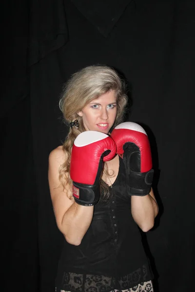 Blonde girl in black casual dress in red boxing gloves — Stock Photo, Image