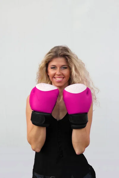 Блондинка в черном платье в розовых боксерских перчатках — стоковое фото