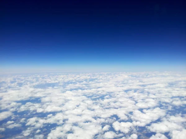 Вид зверху на білі хмари з літака, на тлі чистого блакитного неба — стокове фото