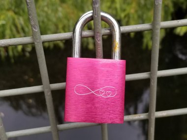 a pink padlock hanging on the railing of the bridge