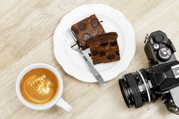 Choklad brownie kaffe latte paus och vintage kamera på woode Stockfoto