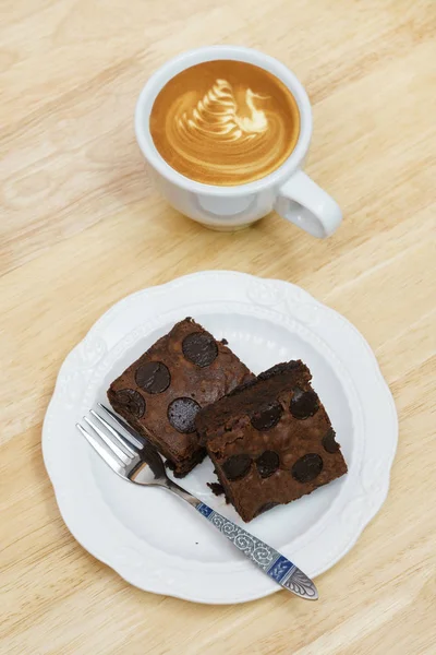 Choklad brownie kaffe latte paus på träbord Stockbild