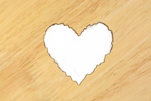 Papel branco em forma de coração queimado na mesa de madeira — Fotografia de Stock