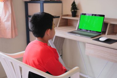 Asyalı çocuk dizüstü bilgisayardan bir şey izlerken evde kalır.