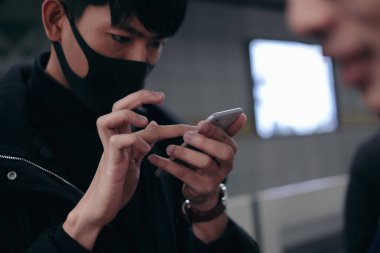 Genç adam metro beklerken akıllı telefon kullanıyor.