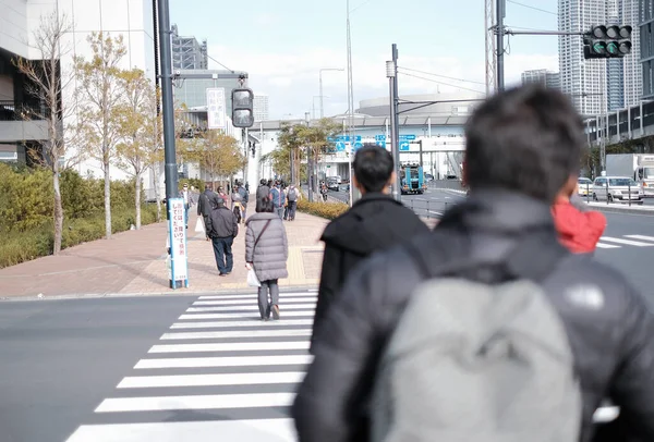 City life in Tokyo, Japan with people walking on sidewalk at noon