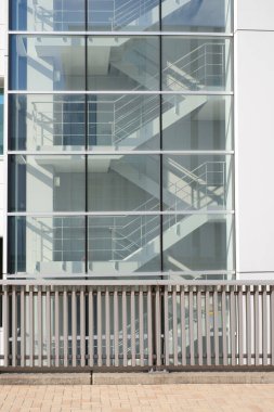 Çıkıştaki binanın içindeki metal merdivenlerin yan görüntüsü pencere camından güneş ışığıyla yer altına bağlanıyor.