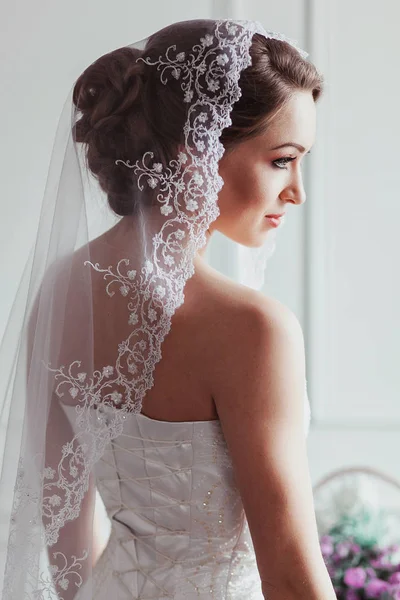 Bela noiva com penteado de casamento de moda - em fundo branco. Retrato de uma jovem. Tiro no estúdio. Menina véu sobre o rosto — Fotografia de Stock