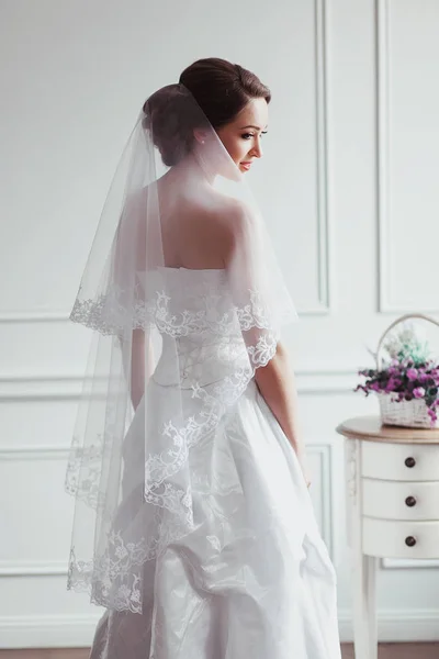 Hermosa novia con peinado de boda de moda - sobre fondo blanco. Retrato de mujer joven. Grabado en estudio. Velo de niña sobre su cara — Foto de Stock